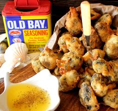 an assortment of food items on a wooden table next to a container of oil and seasoning