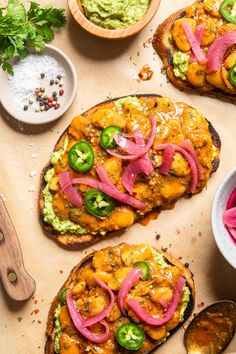 two pieces of bread topped with guacamole and red onions next to bowls of salsa