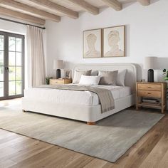 a large white bed sitting in a bedroom on top of a hard wood flooring