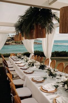 a long table with white linens and place settings