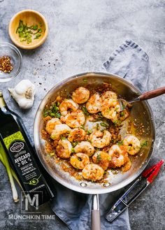 a pan filled with shrimp and vegetables next to a bottle of wine