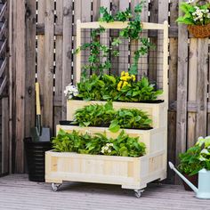 three wooden planters with plants growing in them on top of a deck next to a fence