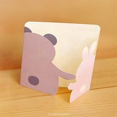 a paper cut out of a bear and bunny on a wooden table with a brown background