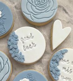 decorated cookies with blue frosting and white icing are arranged on a marble surface