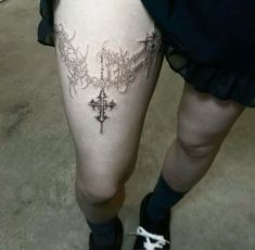 a woman's thigh with an ornate cross tattoo on her lower leg, while wearing black socks