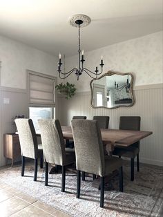 a dining room table with six chairs and a large mirror on the wall above it