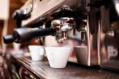 an espresso machine with two cups next to it