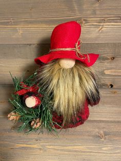 a red hat and beard doll sitting on top of a wooden floor next to pine cones