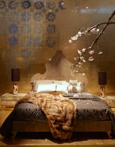 a large bed sitting next to two lamps on top of a wooden floor covered in fur