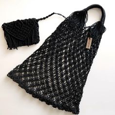 black crochet bag with tassels on white surface next to it's contents