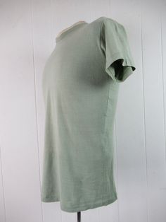 "Vintage 1960s pale sage green cotton t shirt. Plain t shirt with nice natural fade. Torso T shirt by Stedman. Size medium. Actual measurements are: 38\" around the chest 38\" at the waist 16\" shoulder seam to shoulder seam 26\" overall length In very good condition. Tiny faint spot at lower front." Spring Green Washed T-shirt, Washed Short Sleeve Organic Cotton T-shirt, Short Sleeve Washed Organic Cotton T-shirt, Short Sleeve Washed Organic Cotton Tops, Washed Organic Cotton Short Sleeve Tops, Light Wash Washed Cotton T-shirt, Light Washed Cotton T-shirt, Plain Green T-shirt For Spring, Vintage Solid Color Cotton T-shirt