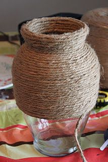 two vases with twine wrapped around them sitting on top of a cloth covered tablecloth