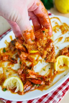 a person is holding up some food on a plate with lemons and ketchup