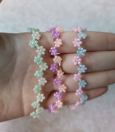 a woman's hand holding several bracelets made out of beads and plastic flowers