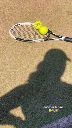 the shadow of a person holding a tennis racket with two balls on top of it