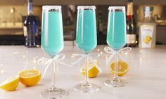 two glasses filled with blue liquid next to lemons on a white counter top and the words tiffany mimosas above them