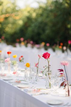 the table is set with flowers in vases and place settings for guests to sit at