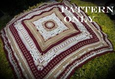 a red and white crocheted blanket sitting on top of grass