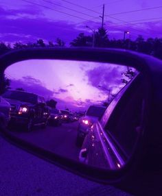 the rear view mirror is reflecting cars in it's side view mirror, with purple hues