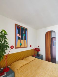 a bed room with a neatly made bed and a painting on the wall