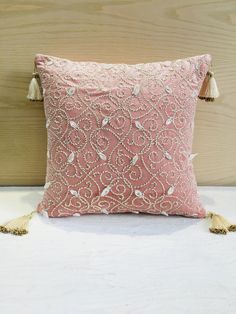 a pink pillow with tassels on it