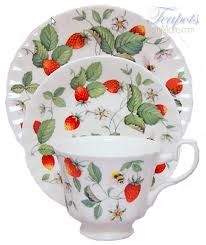 a white plate with strawberries on it and two cups next to eachother