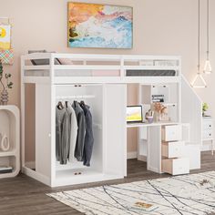 a loft bed with a desk underneath it and clothes hanging on the rails in front of it