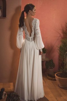 the back of a woman's white dress with long sleeves and lace on it