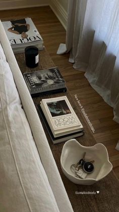 a coffee table with books on it and a bowl sitting next to the couch in front