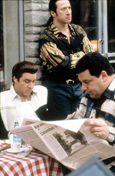 two men sitting at a table reading a newspaper