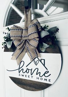 a door hanger with a bow on it that says home sweet home and is decorated with greenery