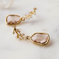 Our Juniper Branch Earrings are perfectly boho chic. They're simple, dainty and won't overpower your entire look on your special day! These also make a perfect gift for bridesmaids for a classic bohemian look.FEATURES Champagne hued glass drops set in 16k gold plating White cubic zirconia encrusted leaf post (925 sterling post) 100% nickel free, can be worn by people with sensitive ears