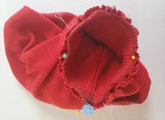 a red knitted hat with buttons attached to the front and back of it, sitting on a white surface