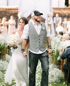 a man and woman holding hands walking down the aisle