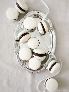 white and black macaroons are on a silver platter next to some string