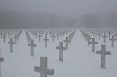 a snow covered cemetery with crosses in the foreground