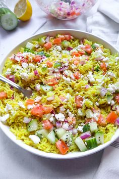 a bowl filled with rice and vegetables on top of a white table cloth next to two bowls