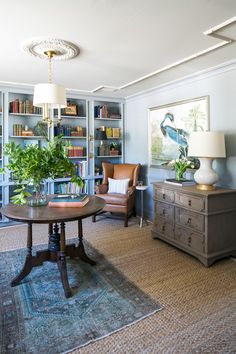 a living room filled with furniture and bookshelves next to a lamp on top of a table