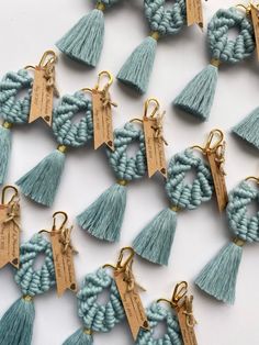 many tassels with tags attached to them on a white surface, one is blue and the other has gold