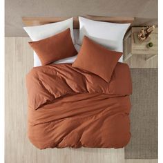 an overhead view of a bed with orange sheets and pillows