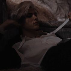 a woman laying on top of a couch holding a knife in her hand and looking at the camera