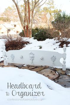 a white bench sitting in the middle of a snow covered yard with trees and bushes