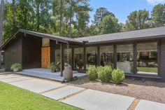 a modern house with large windows in the front yard and landscaping around it, surrounded by trees