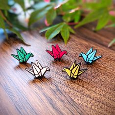 four origami birds sitting on top of a wooden table next to a plant