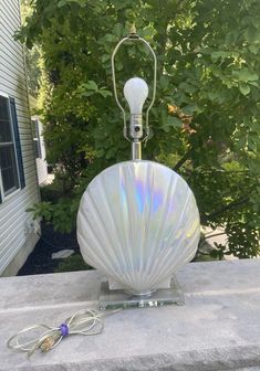 a white shell lamp sitting on top of a cement block