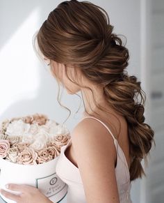 a woman holding a large white box with roses in it's center and her hair pulled back into a pony tail