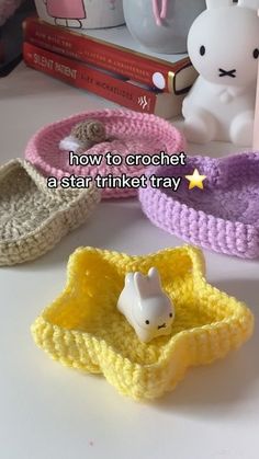 three crocheted baby shoes sitting on top of a table next to a teddy bear