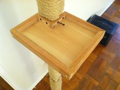 a cat scratching post with a wooden tray on top