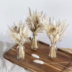 three vases with dried flowers on a tray