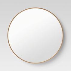 a white round mirror with gold trim around it